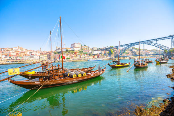 Porto Ribeira skyline Porto, Portugal - August 13, 2017: Picturesque Oporto waterfront. A traditional rabelo boat on Douro River with Dom Luis I Bridge and Ribeira skyline from Vila Nova de Gaia. Sunny day. rabelo boat stock pictures, royalty-free photos & images