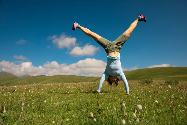 woman doing a handstand in a mountain peak meadow