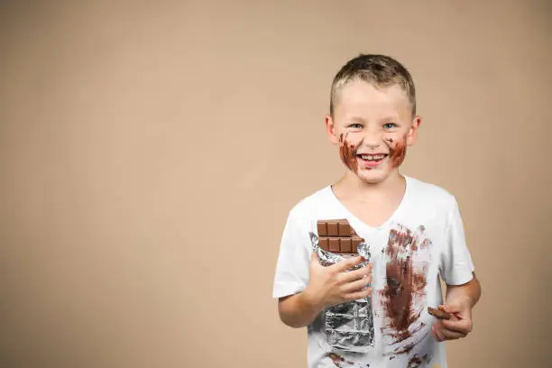 Photo of Little boy holds a bar of chocolate in his hand