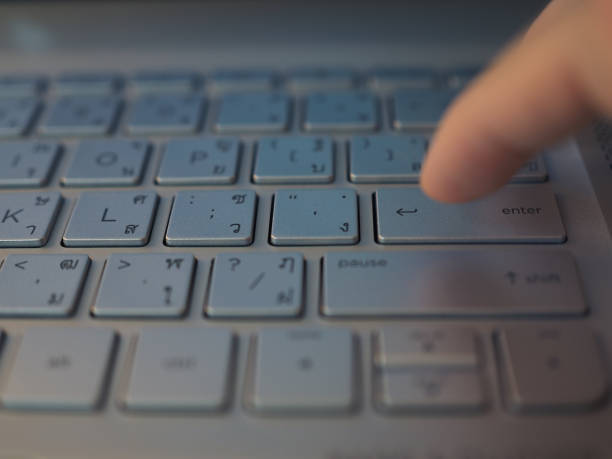 istock Finger pressing Enter button on silver laptop, with Thai letters 861926992