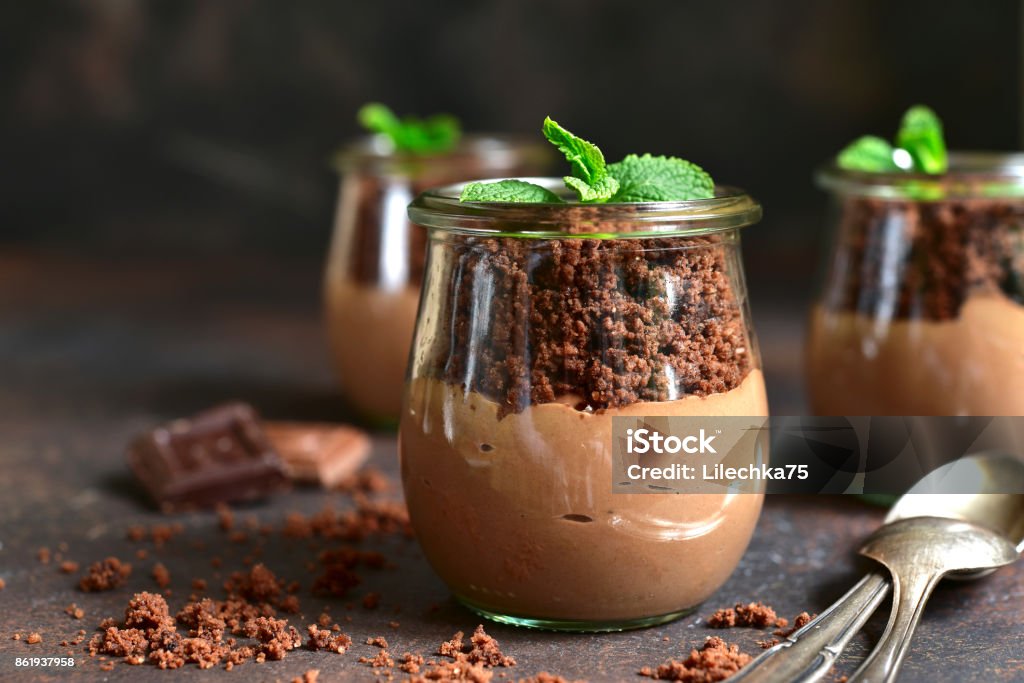 Pots with chocolate pudding,chocolate ground and plant Pots with chocolate pudding,chocolate ground and plant on a dark slate,stone or concrete background- creative funny dessert. Chocolate Stock Photo