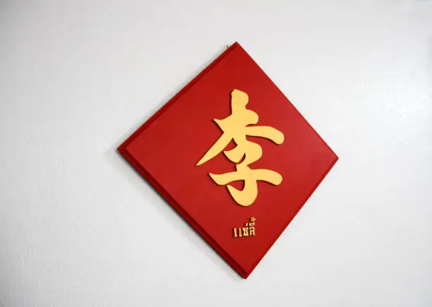 The golden Chinese word handwriting style on the red wooden sign. (Chinese word : Lee, It is a surname, Thai word : surname Lee)
