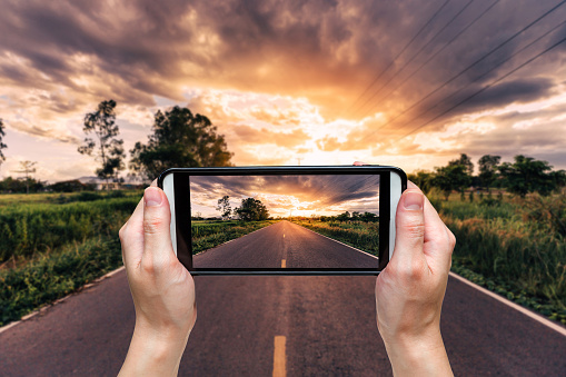 hand woman taking photo at road and sunset.