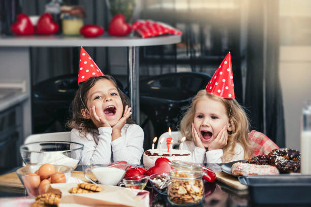 テーブルにケーキで誕生日を祝って 2 つの幸せな小さな女の子の子が素敵な美しい - cake birthday domestic kitchen child ストックフォトと画像