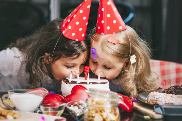 テーブルにケーキで誕生日を祝って 2 つの幸せな小さな女の子の子が素敵な美しい - cake birthday domestic kitchen child ストックフォトと画像