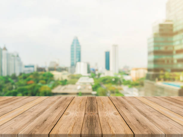 istock Wooden board empty table top blurred background. Perspective brown wood table over blur city building view background - can be used mock up for montage products display or design key visual layout. 861971394