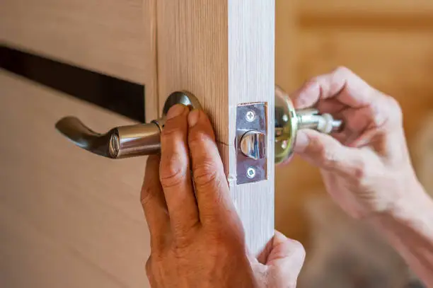 man repairing the doorknob. closeup of worker's hands installing new door locker