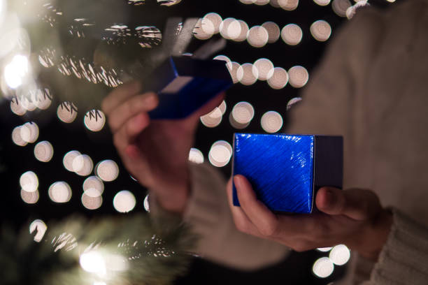 istock Hand female open blue Christmas gift box with bokeh lights background 861979622
