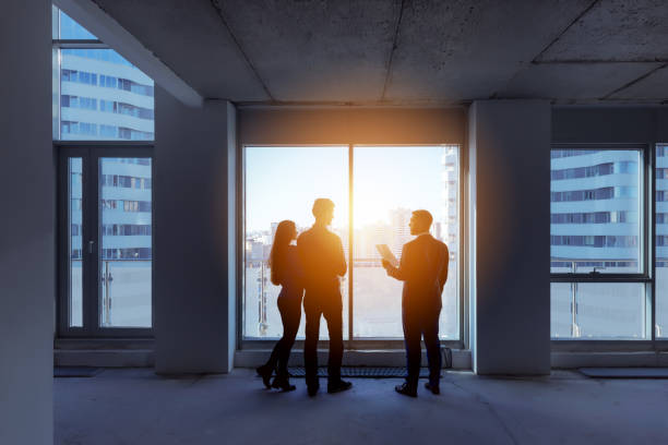 Silhouettes couple real estate agent apartment city Real estate concept with agent and couple near big panoramic window estate worker stock pictures, royalty-free photos & images