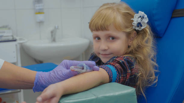 ナースは少女の腕の静脈から血液サンプルを取っています。 - little girls vaccination child caucasian ストックフォトと画像
