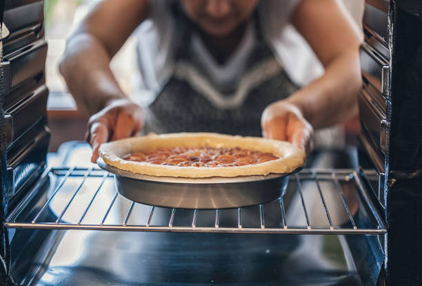 выпечка пекан пирог в духовке для праздников - cooking thanksgiving women baking стоковые фото и изображения