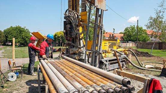 Drilling geothermal well for a residential geothermal heat pump. Workers on Drilling Rig. 