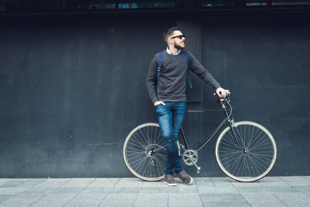 Lifestyle and transportation A young stylish hipster posing next to his bicycle. hipster bike stock pictures, royalty-free photos & images