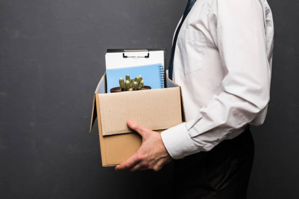 Young handsome businessman in light modern office with carton box. Last day at work. Upset office worker is fired. Young handsome businessman in light modern office with carton box. Upset office worker is fired. fired employee stock pictures, royalty-free photos & images