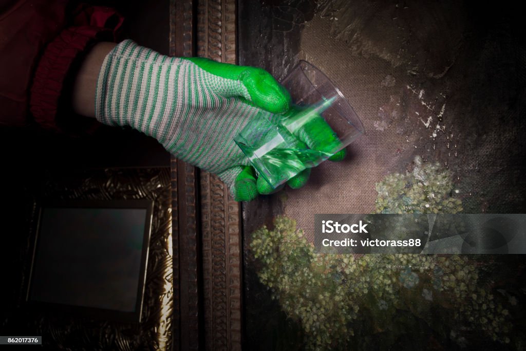 Attacking Artwork Human hand wearing protective gloves attacking the art canvas with a glass of liquid Acid Stock Photo