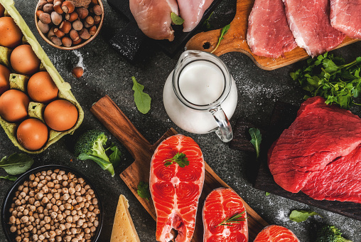 Healthy food background. Selection of protein sources: beef and pork meat, chicken  filet, salmon fish, egg, beans, nuts, milk. Top view copy space, dark background