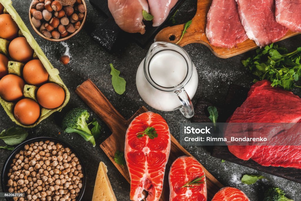 Selection of protein sources food Healthy food background. Selection of protein sources: beef and pork meat, chicken  filet, salmon fish, egg, beans, nuts, milk. Top view copy space, dark background Protein Stock Photo