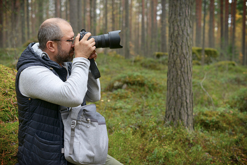 Mature Adult man walking in the woods and take pictures