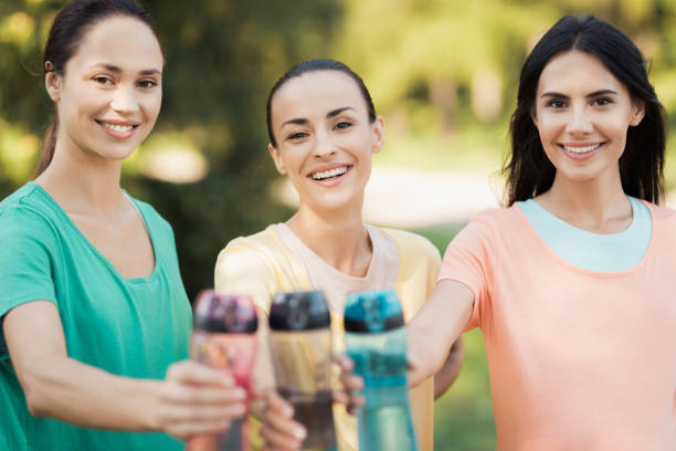 three girls posing in the park putting forward their hands with sports bottles - child women outdoors mother imagens e fotografias de stock