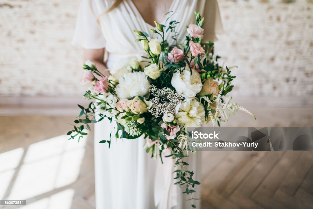 Precioso ramo de flores blancas y rosas en las manos de la novia encantadora en un vestido blanco. Obra de arte - Foto de stock de Boda libre de derechos