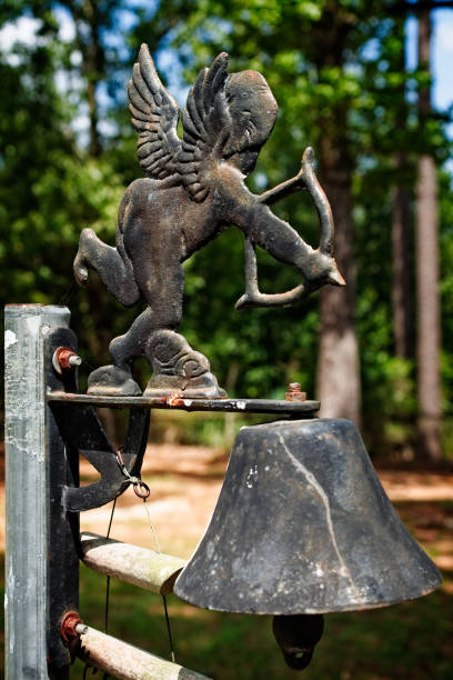 cupido e una campana in un cimitero - sculpture statue cupid gold foto e immagini stock