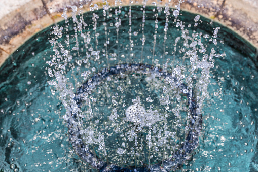 Fountain basin with bubbling up blue water jets from high angle