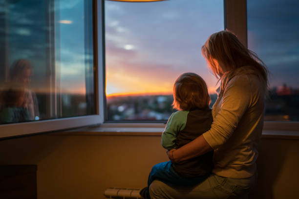 istock back wiew of mom and son looking trough the window 862101624