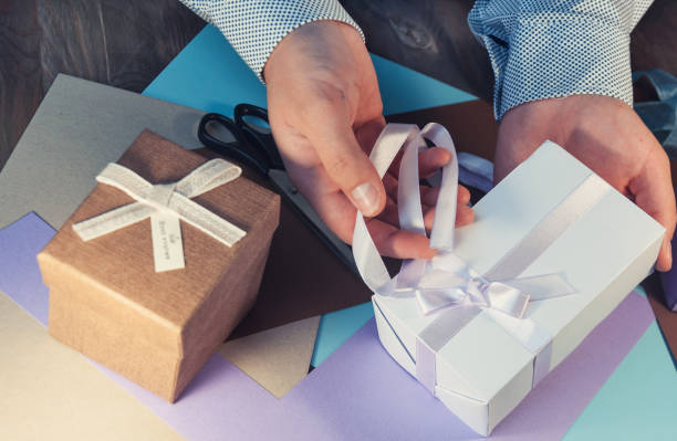 istock A man in a light shirt is preparing a gift box for the holiday. Toning. 862106962