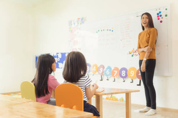 istock Education, elementary school, learning and people concept - group of school kids with teacher sitting in classroom. Vintage effect style pictures. 862111176