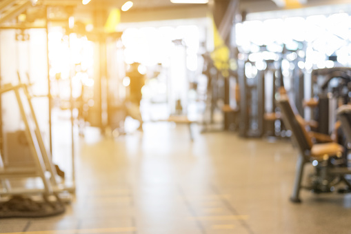 fitness facility center, gym interior, health club with sports training equipment for aerobic exercise workout and bodybuilding, blurry defocused background