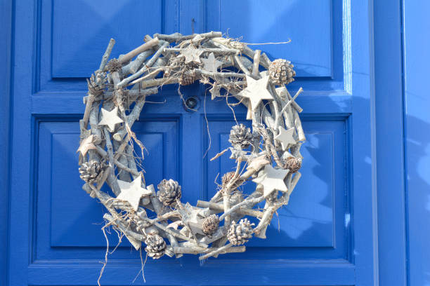 Christmas silver wreath hanging on the blue door. Original New Year Christmas decorations.
