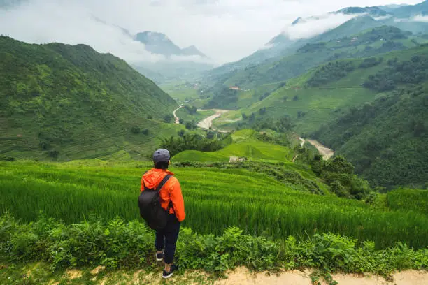 Young traveler standing and looking at view of nature in Sapa, Vietnam in rainy season