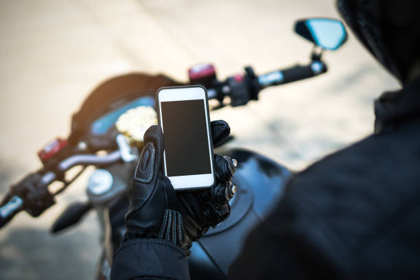biker riding motorbike and holding smart phone stock photo