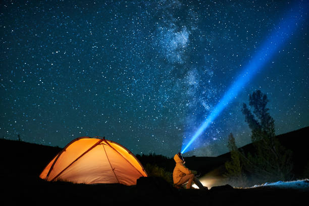 istock Man tourist with flashlight near his camp tent at night. 862152678
