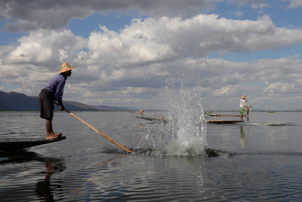 intha pescadores trabajando en su barco flotante golpeando el agua para encontrar peces en myanmar de lago inle en 18 decenber 2016 - inle lake agriculture traditional culture farmer fotografías e imágenes de stock