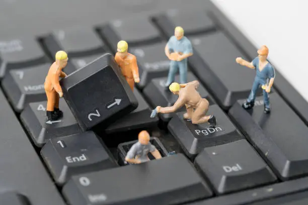 Photo of miniature people Work on Computer Keyboard