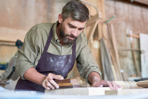 istock Bearded Carpenter Sanding Wood in Shop 862161384