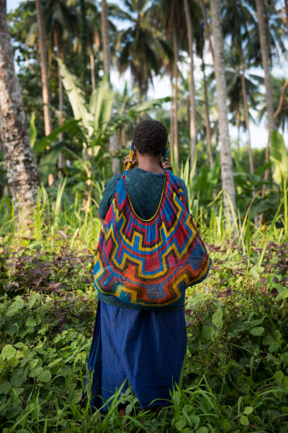 Mother carrying baby in bilum in Papua New Guinea Karkar Island, Papua New Guinea - August 9, 2017: A woman carries her six-month-old daughter, named Joy, in a bilum near Kuduk village on Karkar Island in Madang Province, Papua new Guinea. The bilum is a traditional way to carry a young child in Papua New Guinea. Papua New Guinea stock pictures, royalty-free photos & images