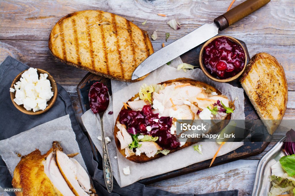 Homemade turkey leftover sandwich with cranberry sauce Homemade leftover thanksgiving day sandwich with turkey, cranberry sauce, feta cheese and vegetables. Top view Leftovers Stock Photo