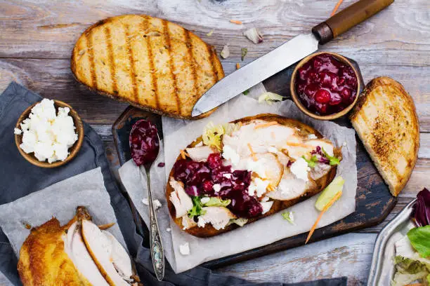 Homemade leftover thanksgiving day sandwich with turkey, cranberry sauce, feta cheese and vegetables. Top view