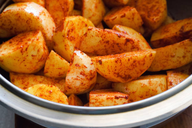 potato wedges with spices and thyme on a metal baking sheet. Top view