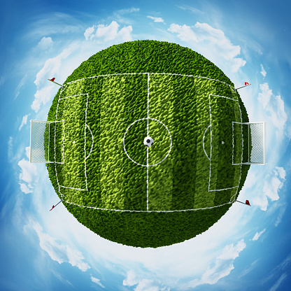 Blue sky surrounding green globe with soccer field covered with green grass.
