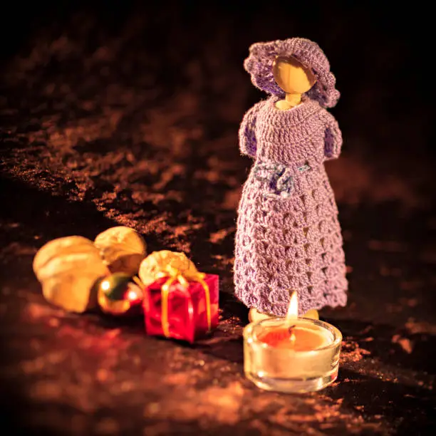 Christmas doll figure with candle and gifts against a brown background