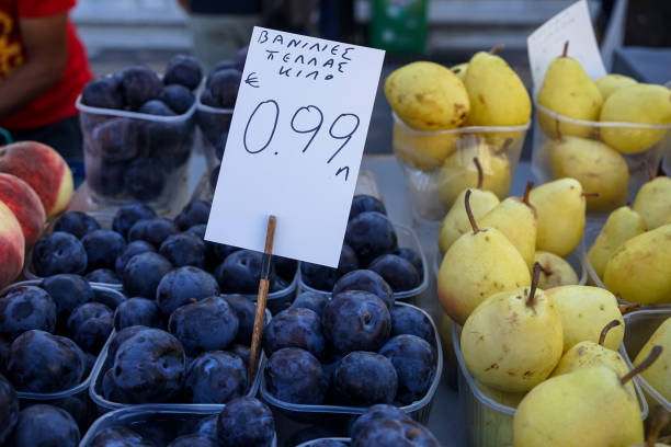 cajas repletas de ciruelos frescos de ámbar negro con capa cerosa blanca polvorienta vendiendo junto a peras y duraznos en el mercado de fruta local de la ciudad - plum yellow eating beauty and health fotografías e imágenes de stock