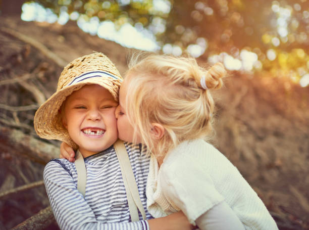 The bond between siblings is an unbreakable one Shot of two little children playing together outdoors kissing stock pictures, royalty-free photos & images
