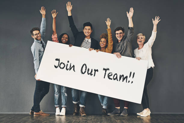 Come and join our team Studio shot of a diverse group of people holding up a placard against a grey background help wanted sign stock pictures, royalty-free photos & images