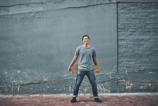 Shot of a young man holding a skateboard outside