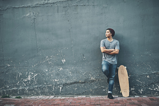 Shot of a young man posing with a skateboard outside