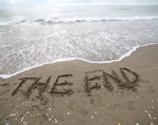 istock THE END text written on the sand and the wave that is deleting t 862202358