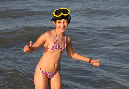 smiling little girl with diving mask plays and dives at the sea in summer